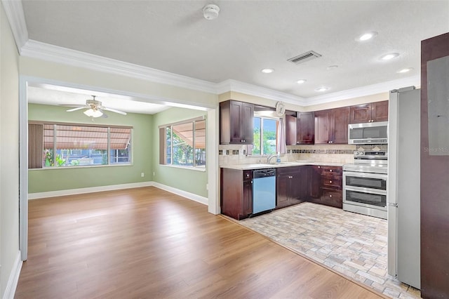 3065 Merrill Ave, Clearwater, FL 33759 - kitchen with stainless steel appliances, crown molding, light countertops, dark brown cabinets, and baseboards