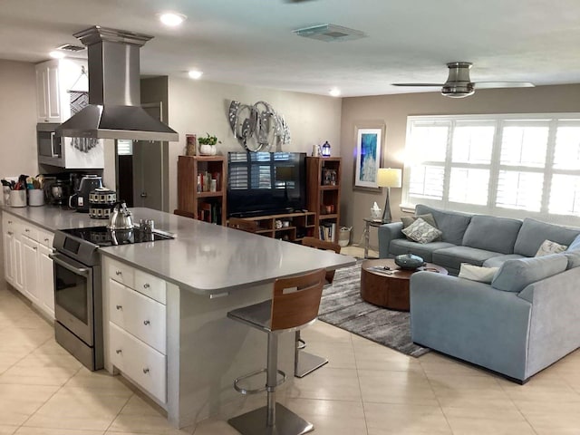 101 Madonna Blvd, Saint Petersburg, FL 33715 - kitchen with white cabinets, stainless steel appliances, island exhaust hood, visible vents, and light tile patterned floors