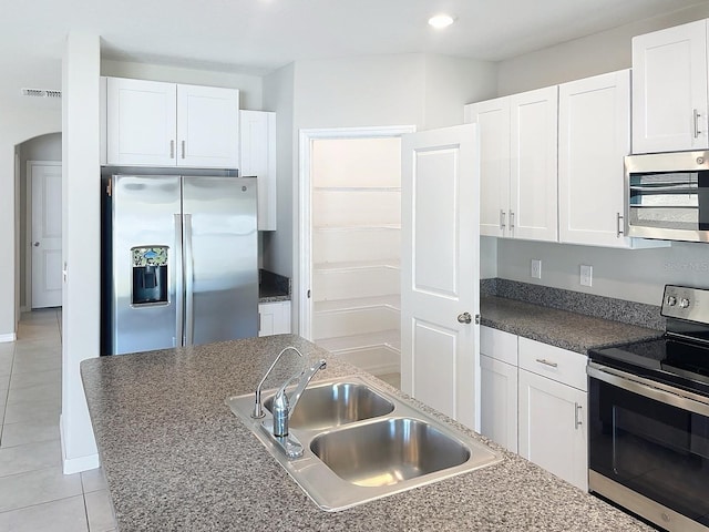 4456 Globe Thistle Dr, Tampa, FL 33619 - kitchen featuring stainless steel appliances, light tile patterned floors, white cabinets, recessed lighting, and dark countertops