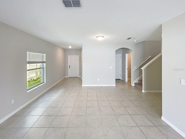 4456 Globe Thistle Dr, Tampa, FL 33619 - unfurnished room with arched walkways, stairs, and light tile patterned floors