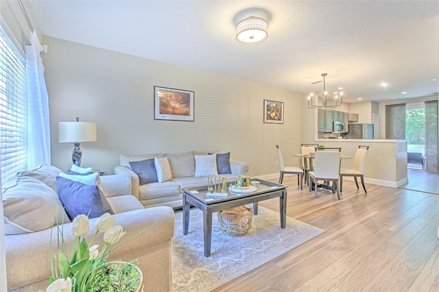 living room featuring recessed lighting, baseboards, a chandelier, and light wood-style floors