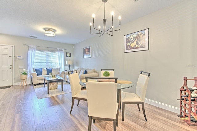 dining room featuring visible vents, light wood-style floors, a notable chandelier, and baseboards