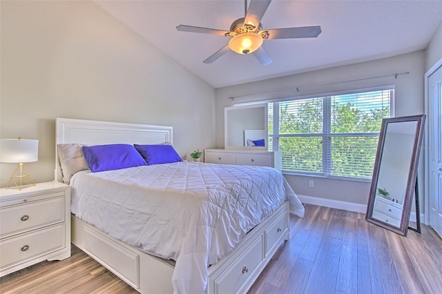 bedroom with baseboards, a ceiling fan, light wood-style floors, and vaulted ceiling