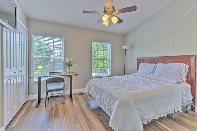 bedroom with multiple windows, wood finished floors, and baseboards