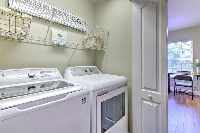 clothes washing area featuring washing machine and dryer, laundry area, and wood finished floors