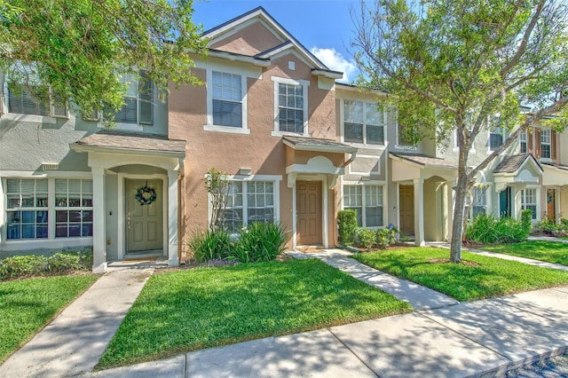 townhome / multi-family property featuring stucco siding and a front lawn
