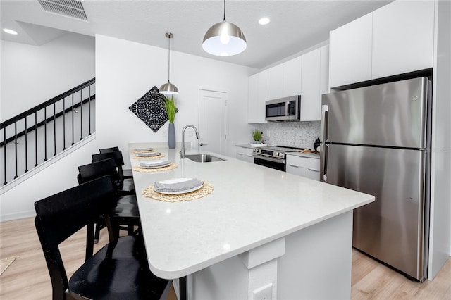 3402 E 28th Ave Unit 6, Tampa, FL 33605 - kitchen with stainless steel appliances, light wood-style floors, light countertops, white cabinets, and backsplash