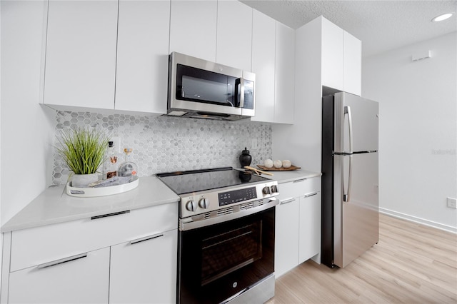 3402 E 28th Ave Unit 6, Tampa, FL 33605 - kitchen with appliances with stainless steel finishes, light countertops, white cabinets, light wood-style floors, and modern cabinets