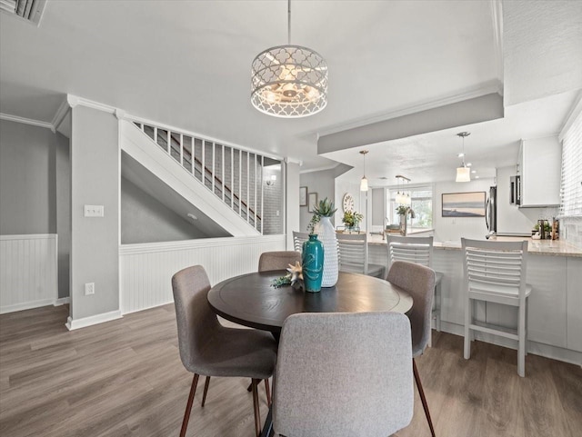 619 2nd St Unit 3, Indian Rocks Beach, FL 33785 - dining area with crown molding, a wainscoted wall, wood finished floors, stairs, and a chandelier