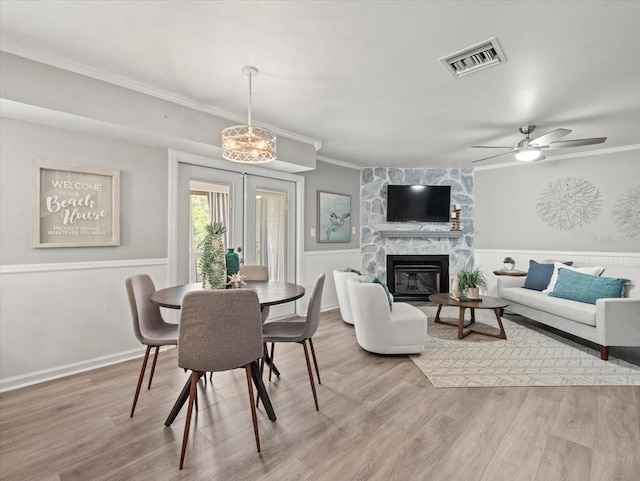 619 2nd St Unit 3, Indian Rocks Beach, FL 33785 - dining room featuring ornamental molding, wainscoting, wood finished floors, a stone fireplace, and a ceiling fan