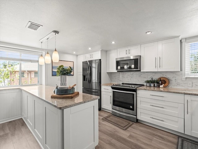 619 2nd St Unit 3, Indian Rocks Beach, FL 33785 - kitchen with stainless steel appliances, light wood finished floors, white cabinetry, a textured ceiling, and decorative backsplash