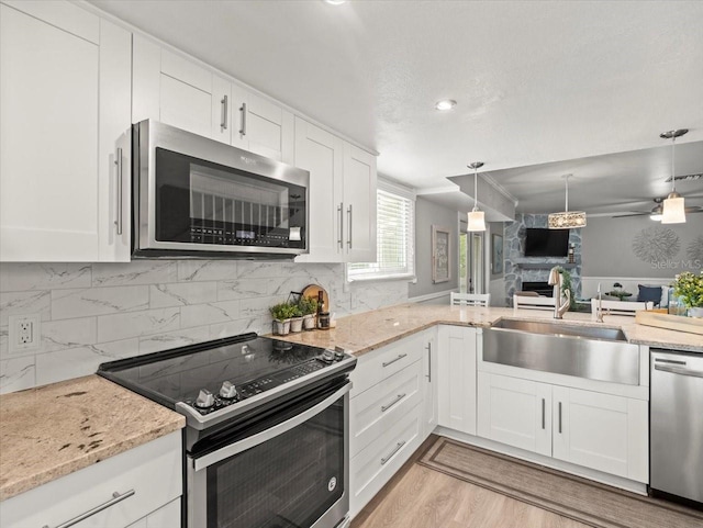 619 2nd St Unit 3, Indian Rocks Beach, FL 33785 - kitchen with appliances with stainless steel finishes, a sink, a large fireplace, white cabinets, and light stone countertops