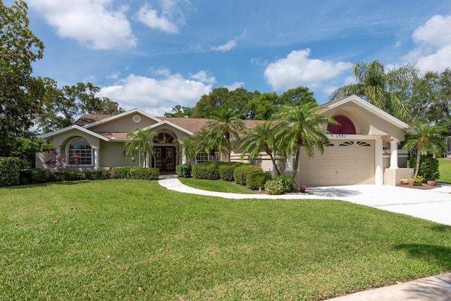 view of front of home featuring driveway, french doors, a front yard, a garage, and stucco siding