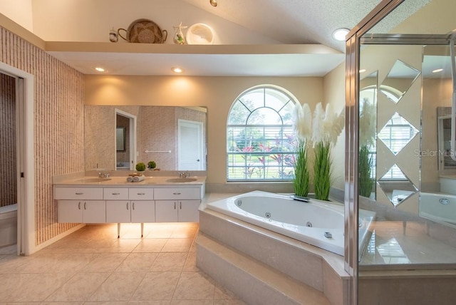 full bathroom featuring lofted ceiling, tile patterned flooring, double vanity, a jetted tub, and a sink