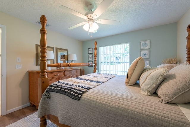 bedroom with ceiling fan, baseboards, wood finished floors, and a textured ceiling