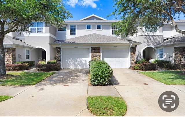 view of front of home with stucco siding, driveway, and stone siding