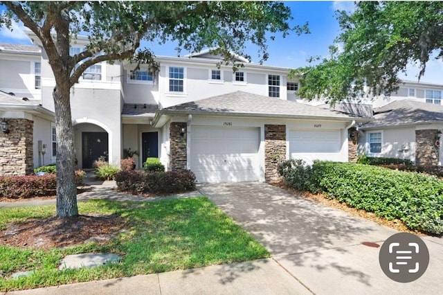 view of front of property with stucco siding, an attached garage, driveway, and stone siding