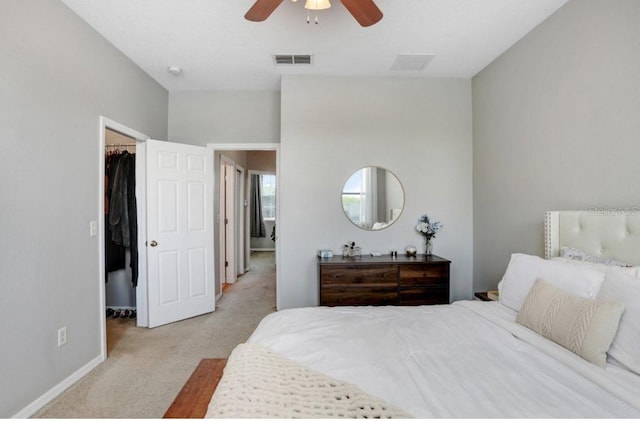 bedroom with a walk in closet, carpet floors, visible vents, and baseboards