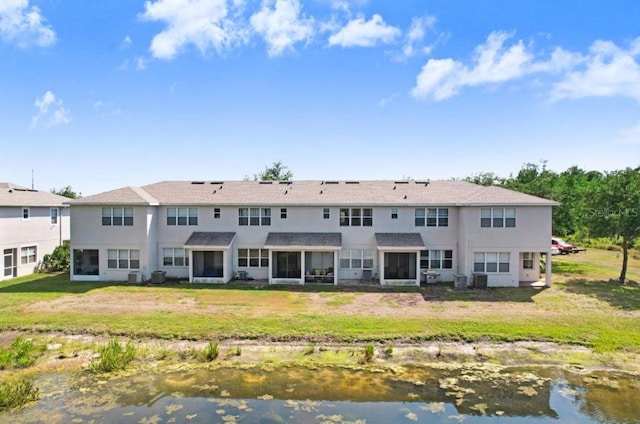 back of property featuring central AC, a water view, stucco siding, a lawn, and a sunroom
