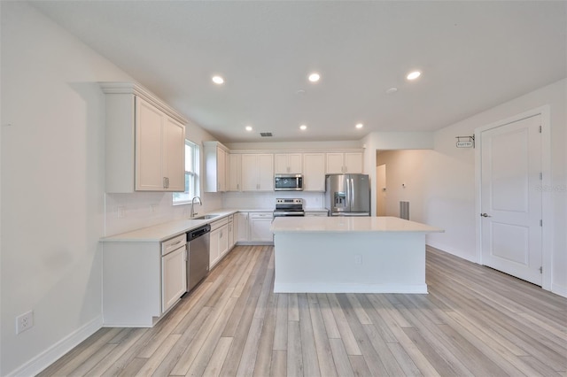 36959 Highland Meadows Ct, Zephyrhills, FL 33542 - kitchen featuring appliances with stainless steel finishes, a sink, light wood-type flooring, a kitchen island, and light countertops