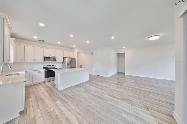36959 Highland Meadows Ct, Zephyrhills, FL 33542 - kitchen with stainless steel appliances, a sink, a kitchen island, light countertops, and light wood-style floors