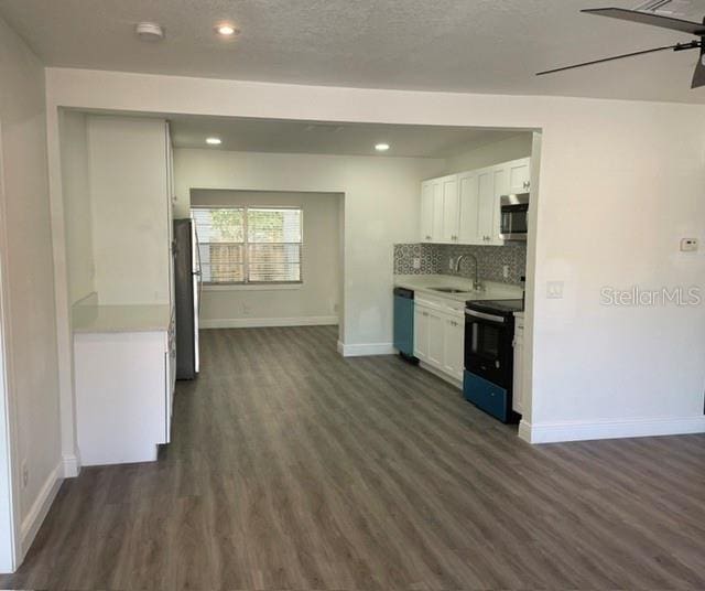 kitchen featuring a sink, appliances with stainless steel finishes, light countertops, baseboards, and a ceiling fan