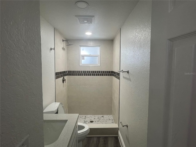 bathroom with a stall shower, toilet, and a textured wall
