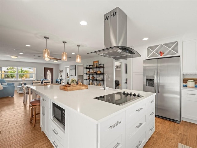 kitchen with appliances with stainless steel finishes, island exhaust hood, open floor plan, and recessed lighting