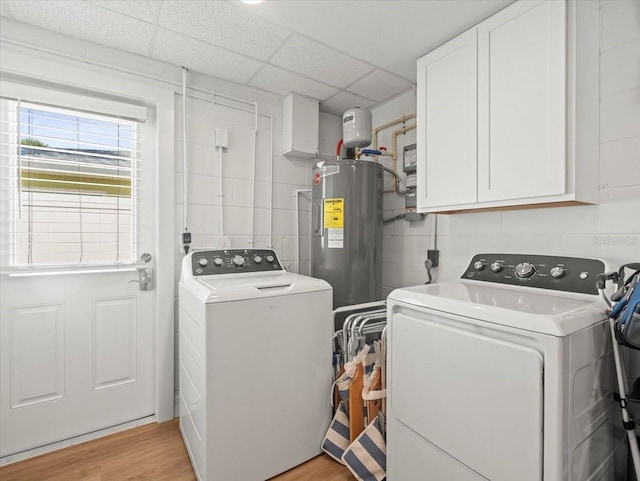 laundry area with electric water heater, light wood-style floors, cabinet space, and washer and clothes dryer