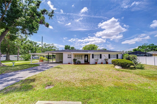 single story home featuring a front lawn, a carport, driveway, and fence