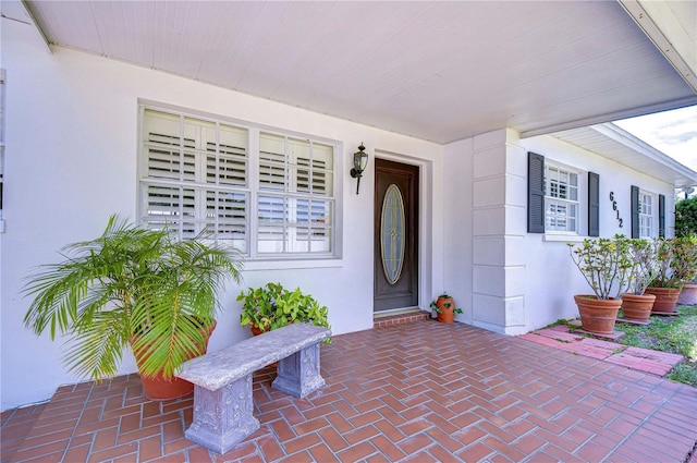 doorway to property featuring stucco siding and covered porch