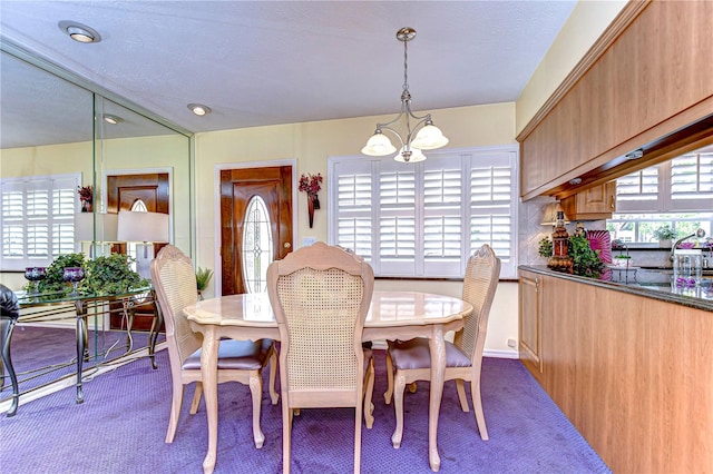 dining space with dark carpet and a chandelier
