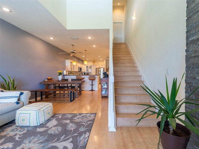 stairway with recessed lighting, wood finished floors, and ceiling fan