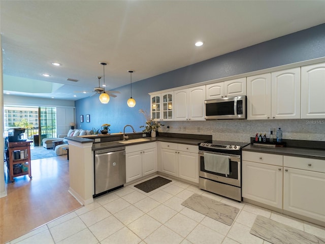 kitchen with appliances with stainless steel finishes, dark countertops, ceiling fan, and a sink