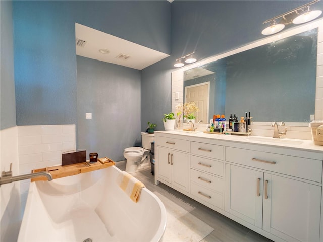 bathroom featuring a tub, double vanity, toilet, a sink, and visible vents