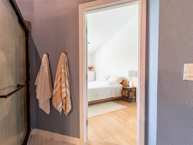 bedroom featuring wood finished floors and a textured wall