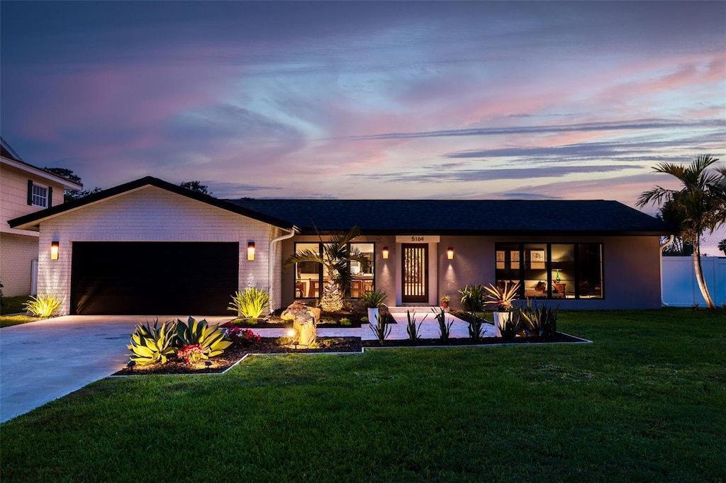 ranch-style home with driveway, a front lawn, and an attached garage
