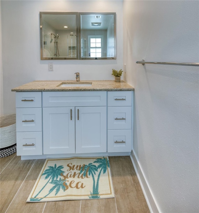 8635 Boca Ciega Dr, St Pete Beach, FL 33706 - bathroom with vanity, baseboards, wood finished floors, and a shower stall