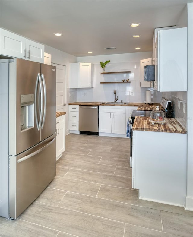 8635 Boca Ciega Dr, St Pete Beach, FL 33706 - kitchen with a sink, decorative backsplash, white cabinets, and stainless steel appliances