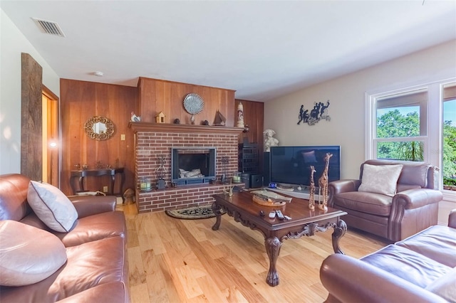 living area with visible vents, a brick fireplace, wood finished floors, and wooden walls