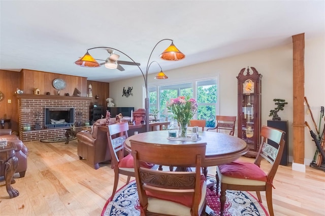 dining space with a fireplace, a ceiling fan, and light wood-type flooring