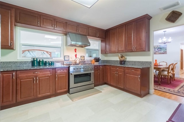 kitchen featuring high end stainless steel range, dark stone counters, light floors, under cabinet range hood, and visible vents
