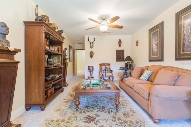 living room with baseboards, ceiling fan, and light carpet
