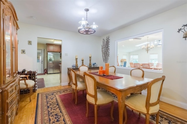 dining space featuring baseboards, a chandelier, and light wood-style floors