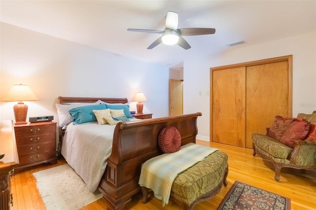 bedroom with ceiling fan, visible vents, light wood finished floors, and a closet