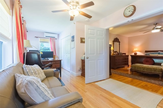 interior space featuring light wood-style floors, a closet, ceiling fan, and an AC wall unit