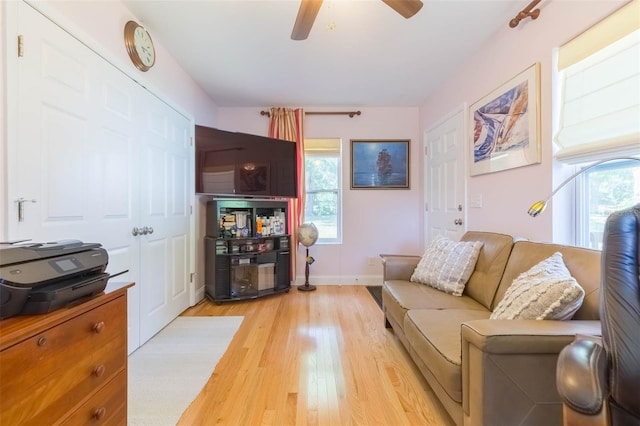 living area featuring a ceiling fan, baseboards, a wealth of natural light, and light wood finished floors