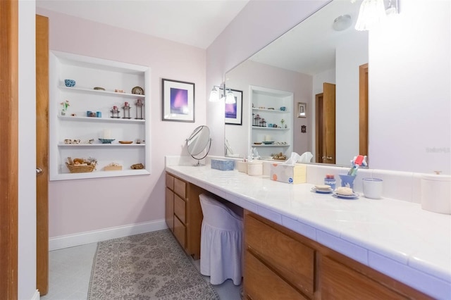 bathroom with vanity, baseboards, and built in shelves