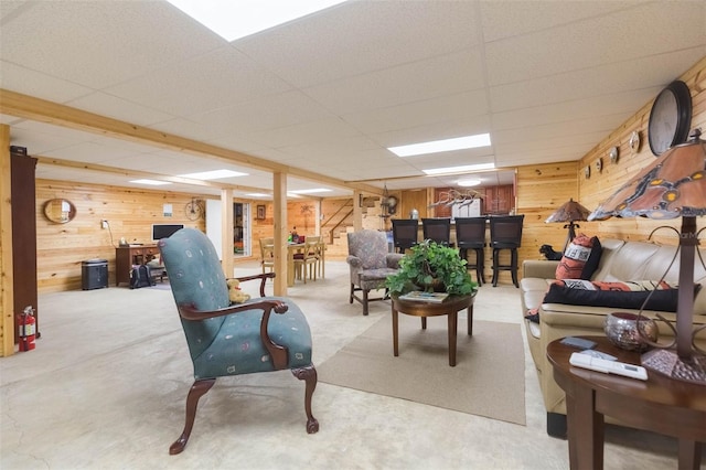 living room featuring carpet flooring, wood walls, and a drop ceiling