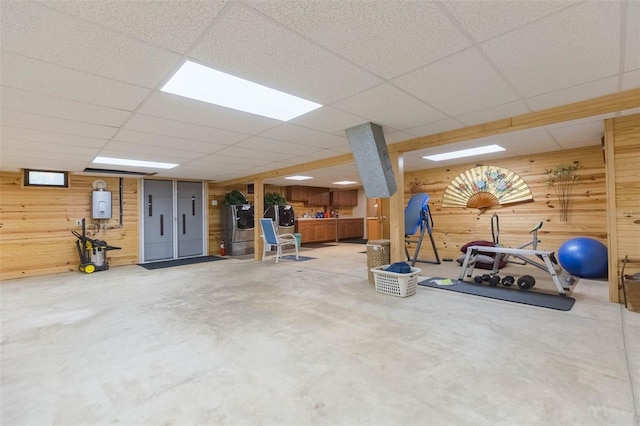 exercise room featuring wooden walls and a drop ceiling
